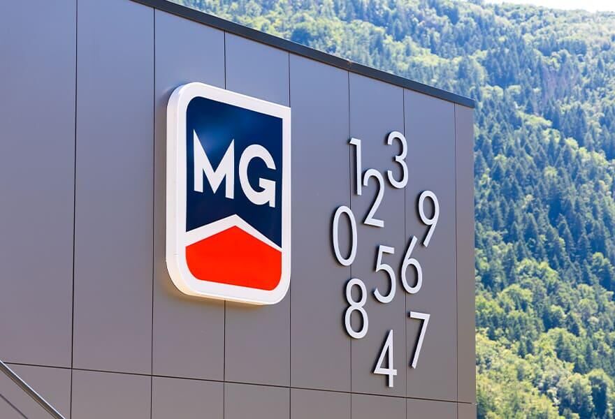 Enseigne MG avec logo et vue sur les montagnes