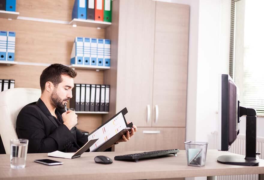 Archivage de documents comptables dans le bureau d'un chef d'entreprise.